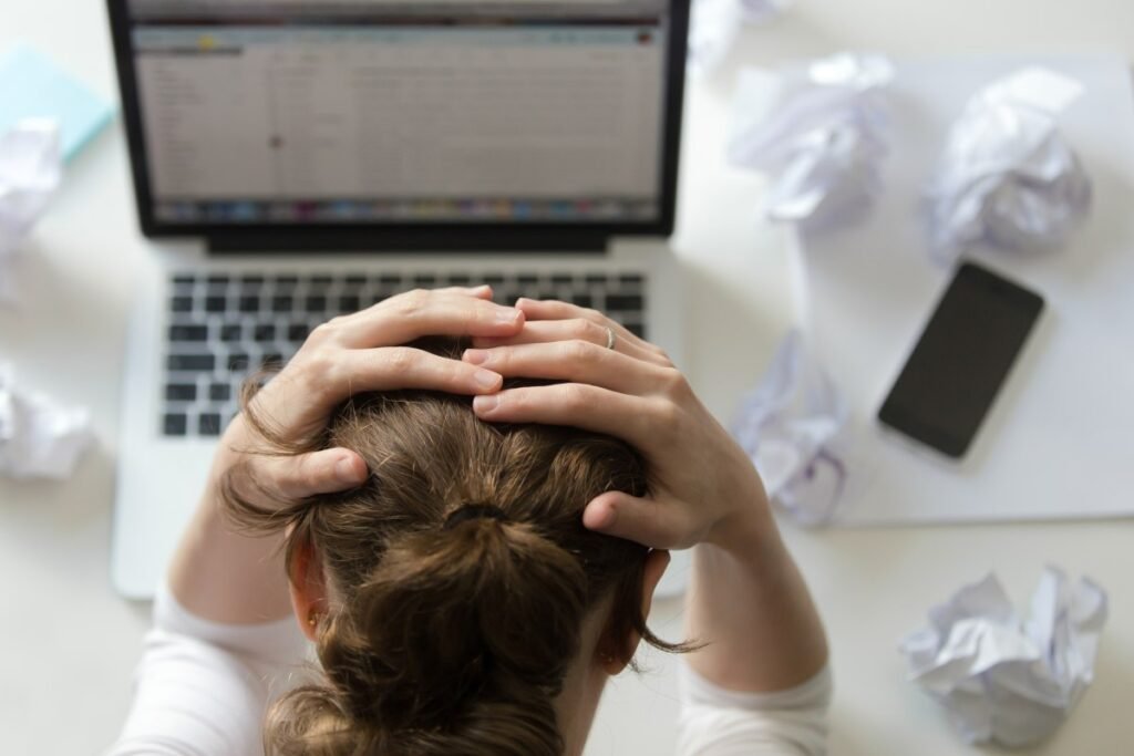 portrait-woman-grabbing-head-desk-near-laptop